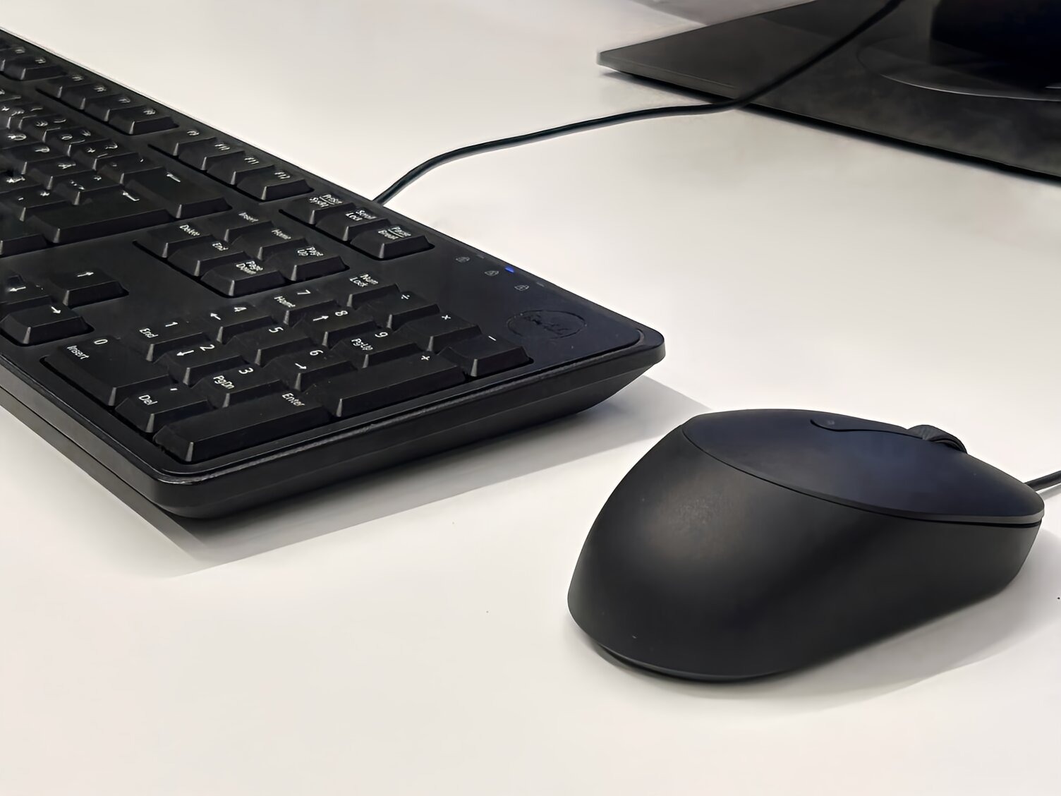 白いデスク上に黒いキーボードとマウスがある。