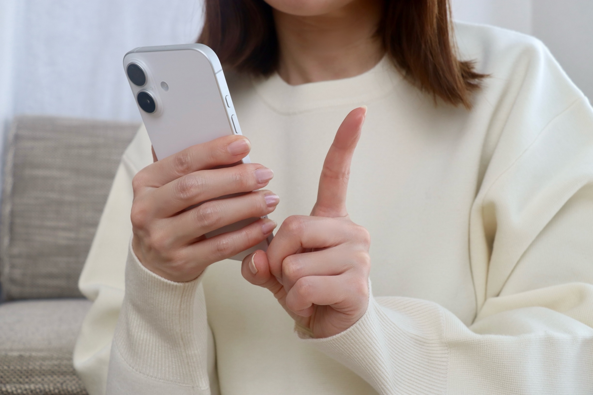 顔は映っていないが、右手にスマホをもって左手で指さしている女性