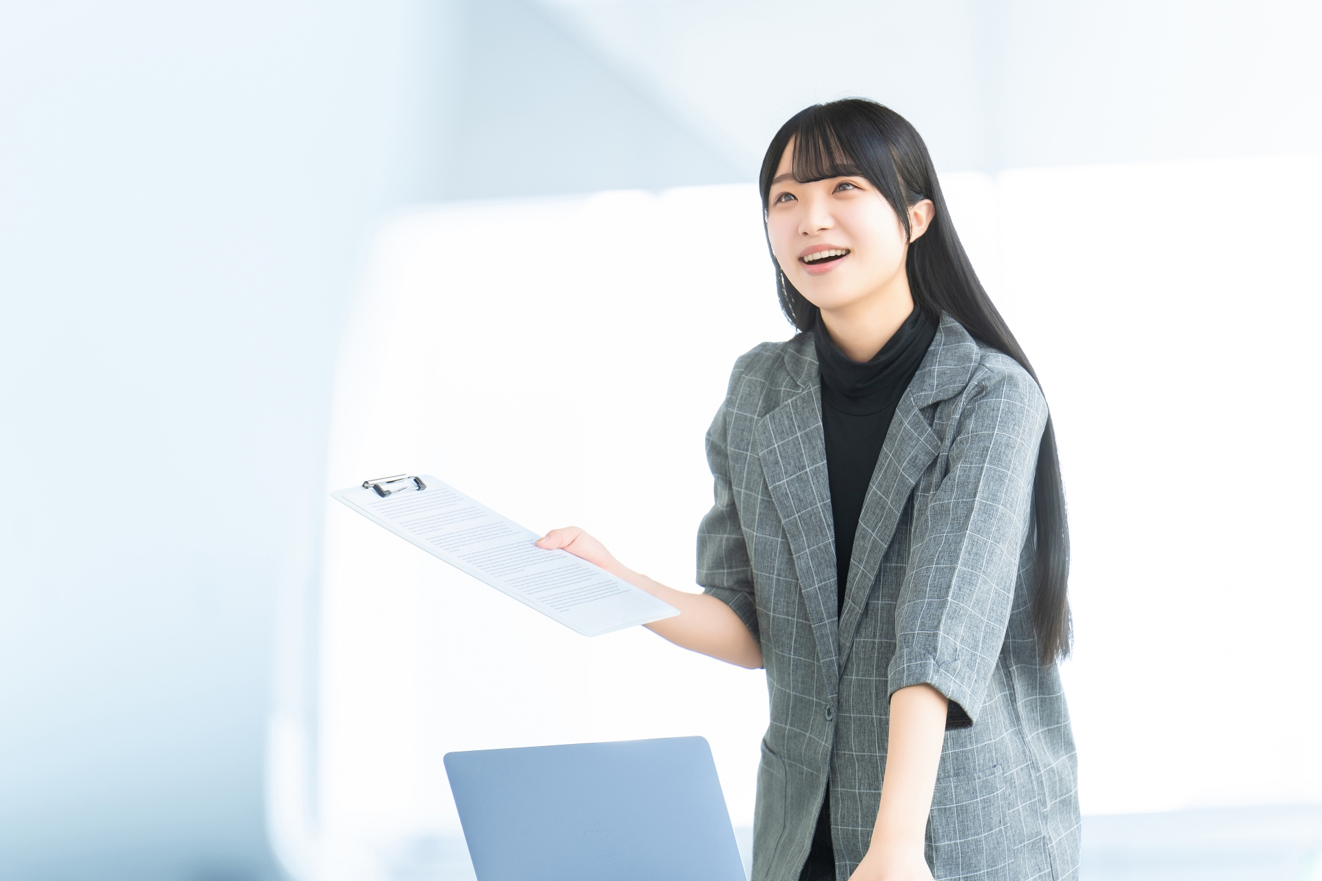 バインダーを右手に持ったスーツを着ている女性