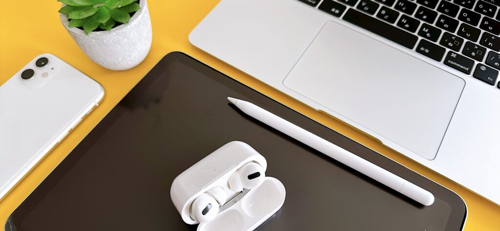 黄色い机の上にmacbookと黒いマウスパッドがある。