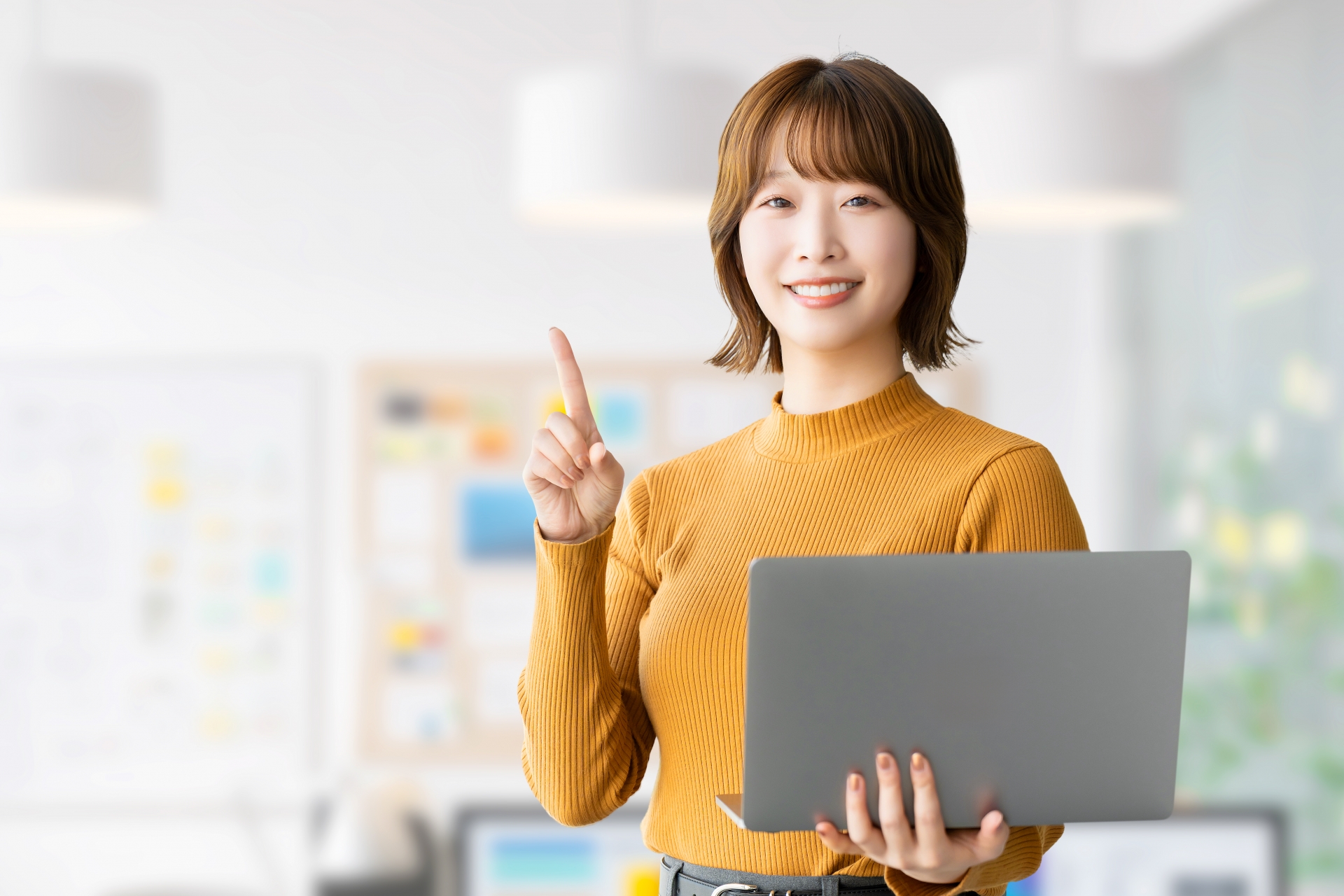 PCを持っているオレンジ色のセーターを着た女性