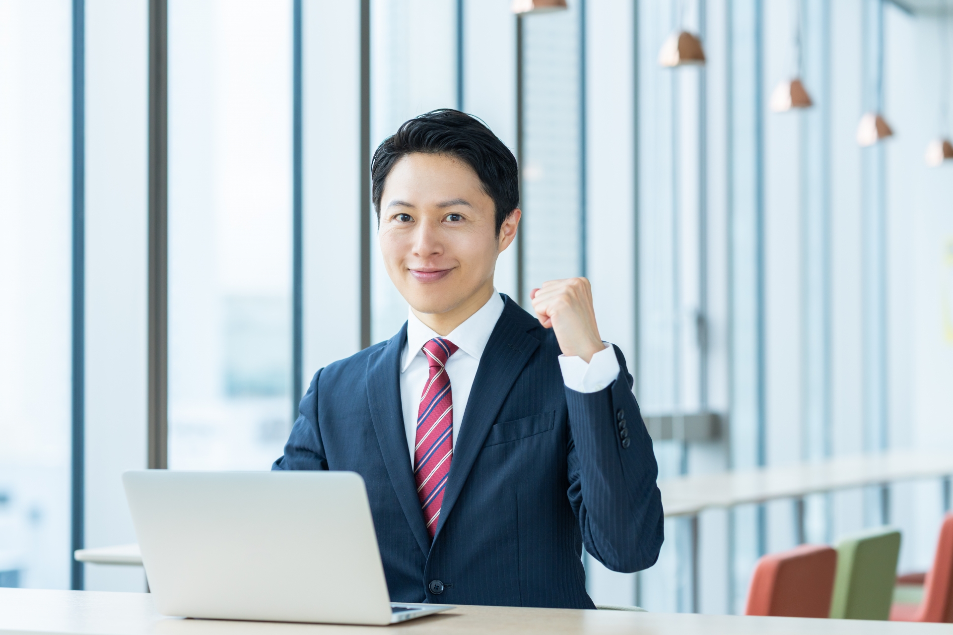 PCの前で左こぶしを握り締めているスーツの男性