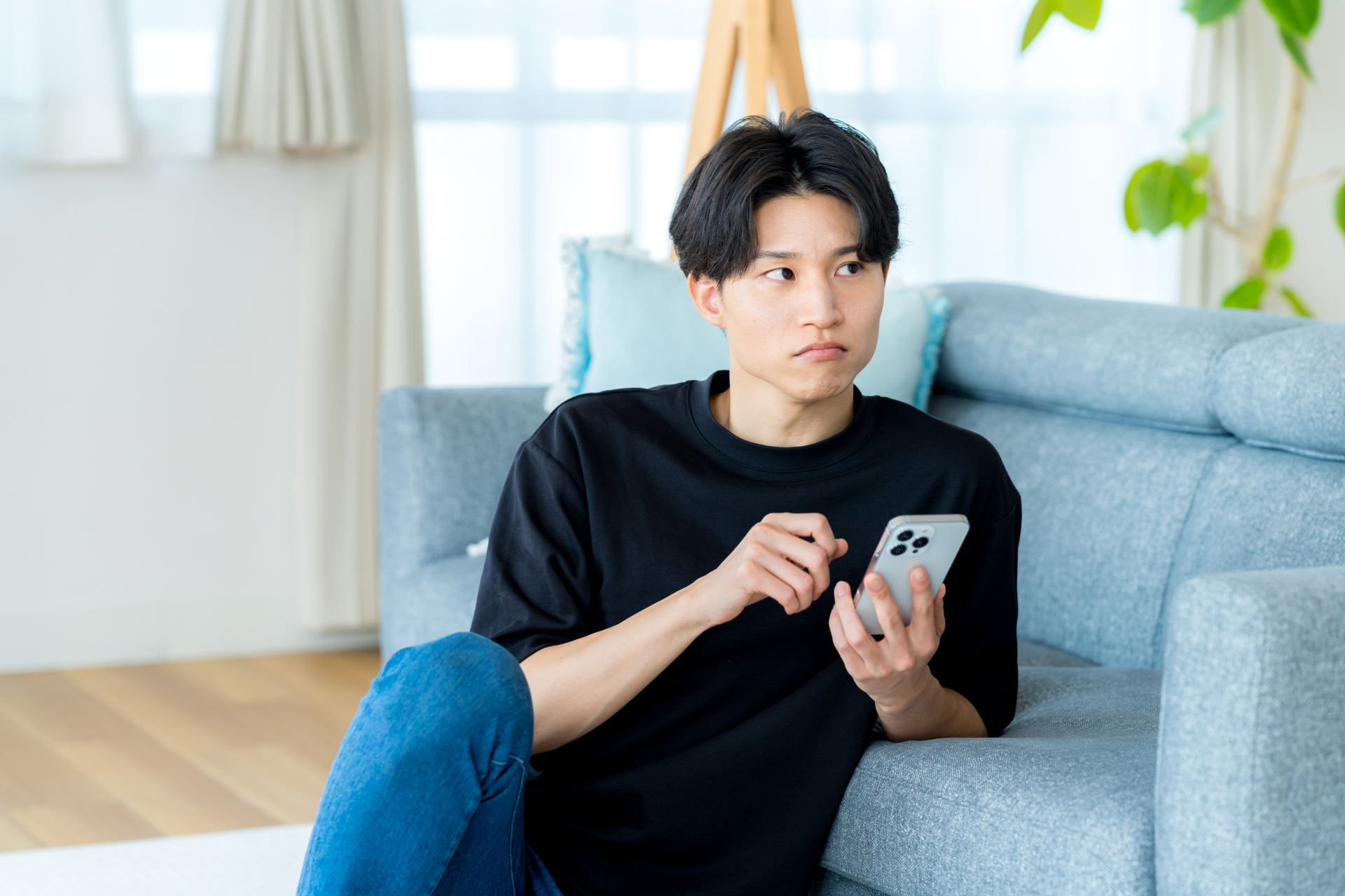 スマホを片手に考え事をしている男性