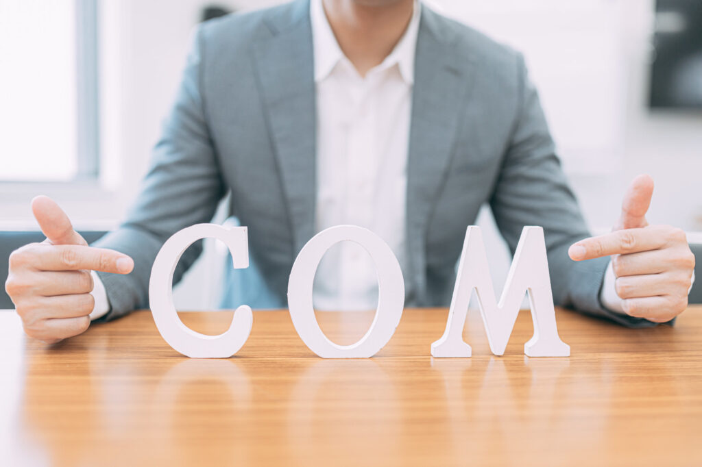 COMという文字の物体を、スーツを着た人が指さしている