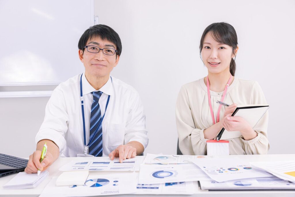 オフィスカジュアルな男女がこちらを机越しに見つめている