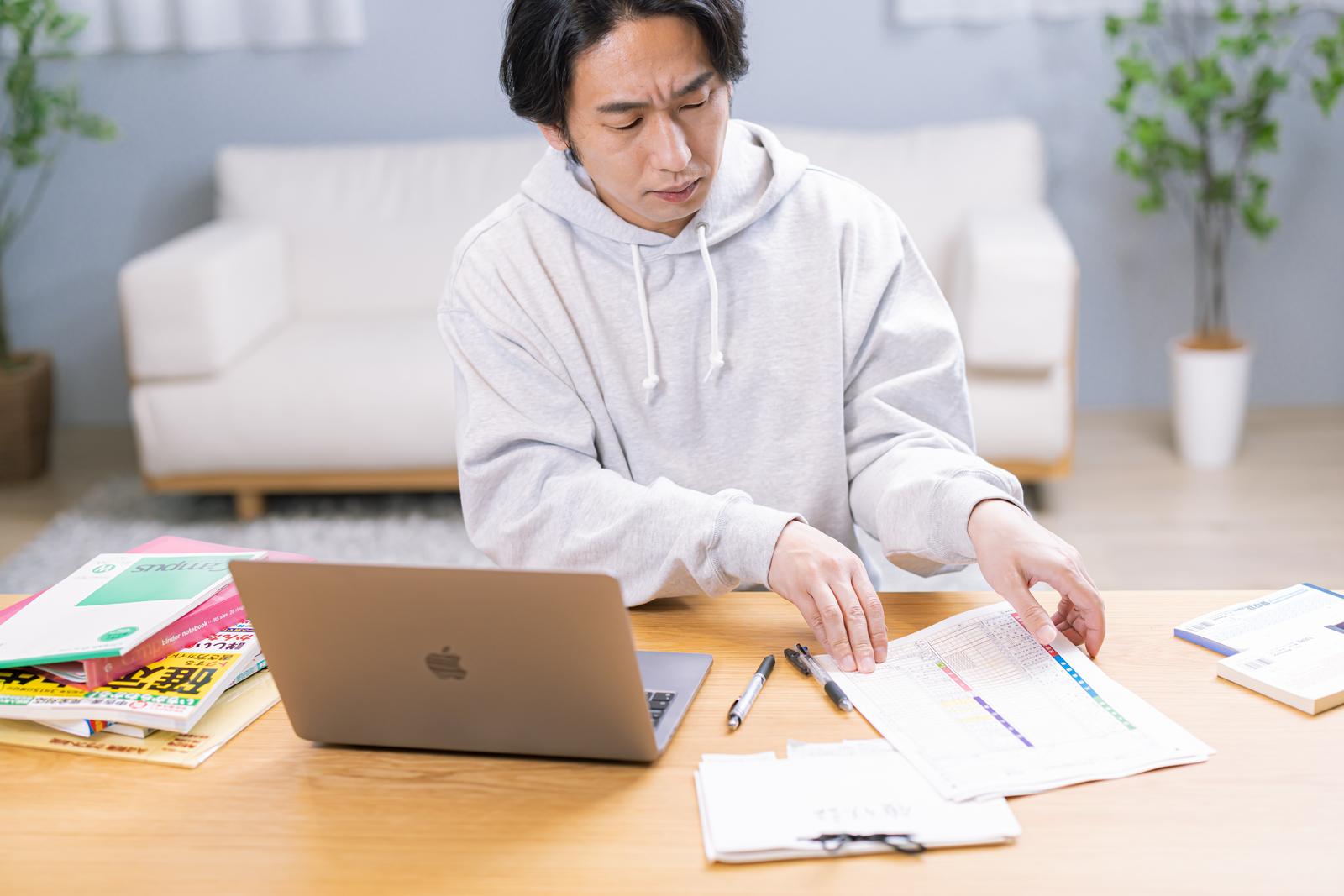 PCや資料の前で眉間に皺を寄せて悩む男性