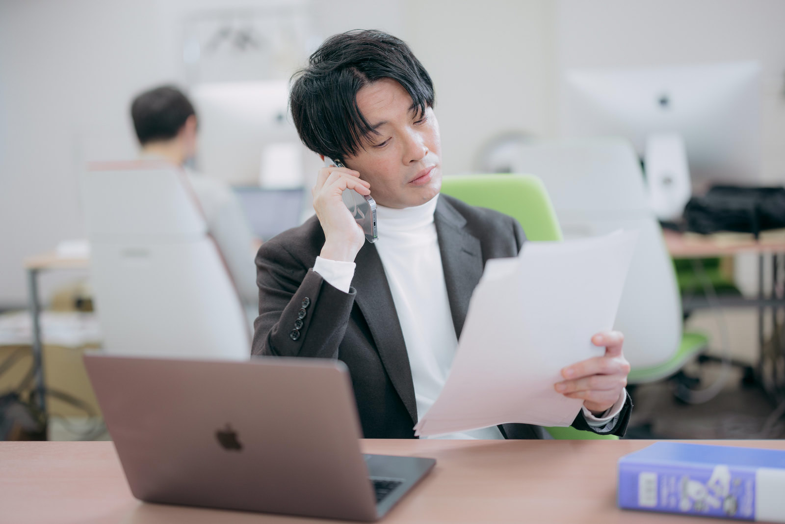 男性が資料を片手に電話をしている。