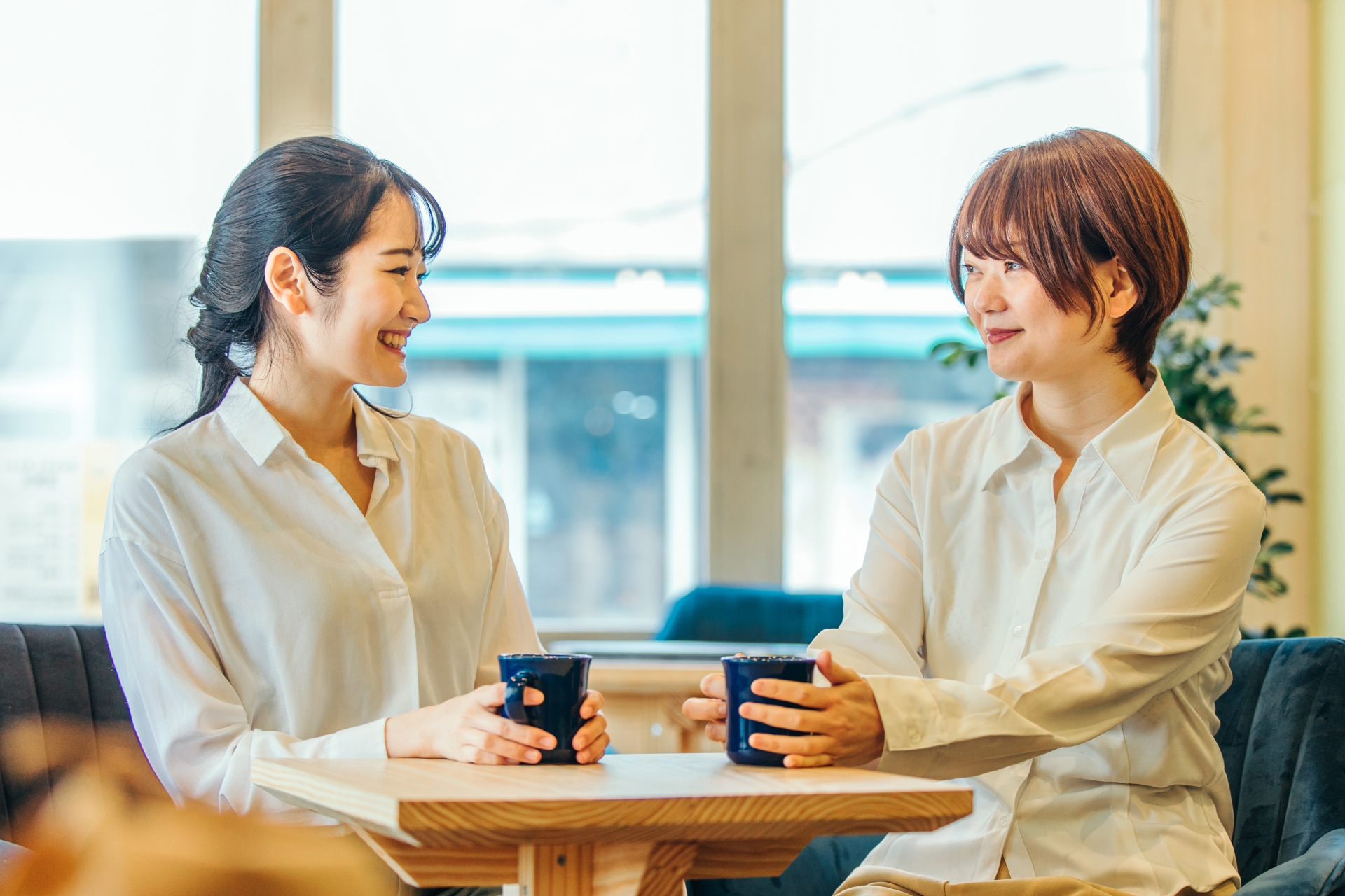 ビジネスカジュアルの女性2人が向かい合っている。