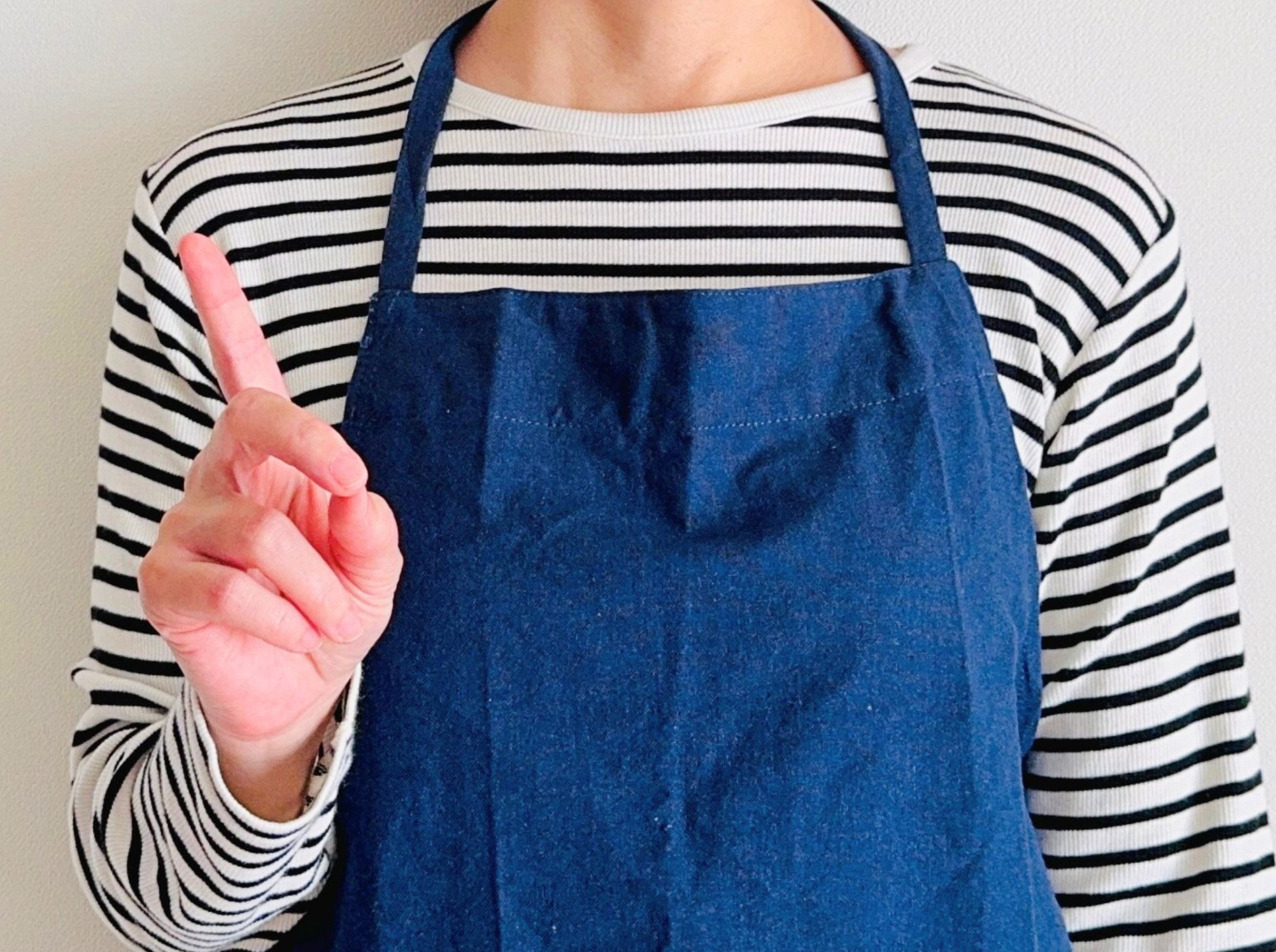 指を指しているエプロンを着た人物