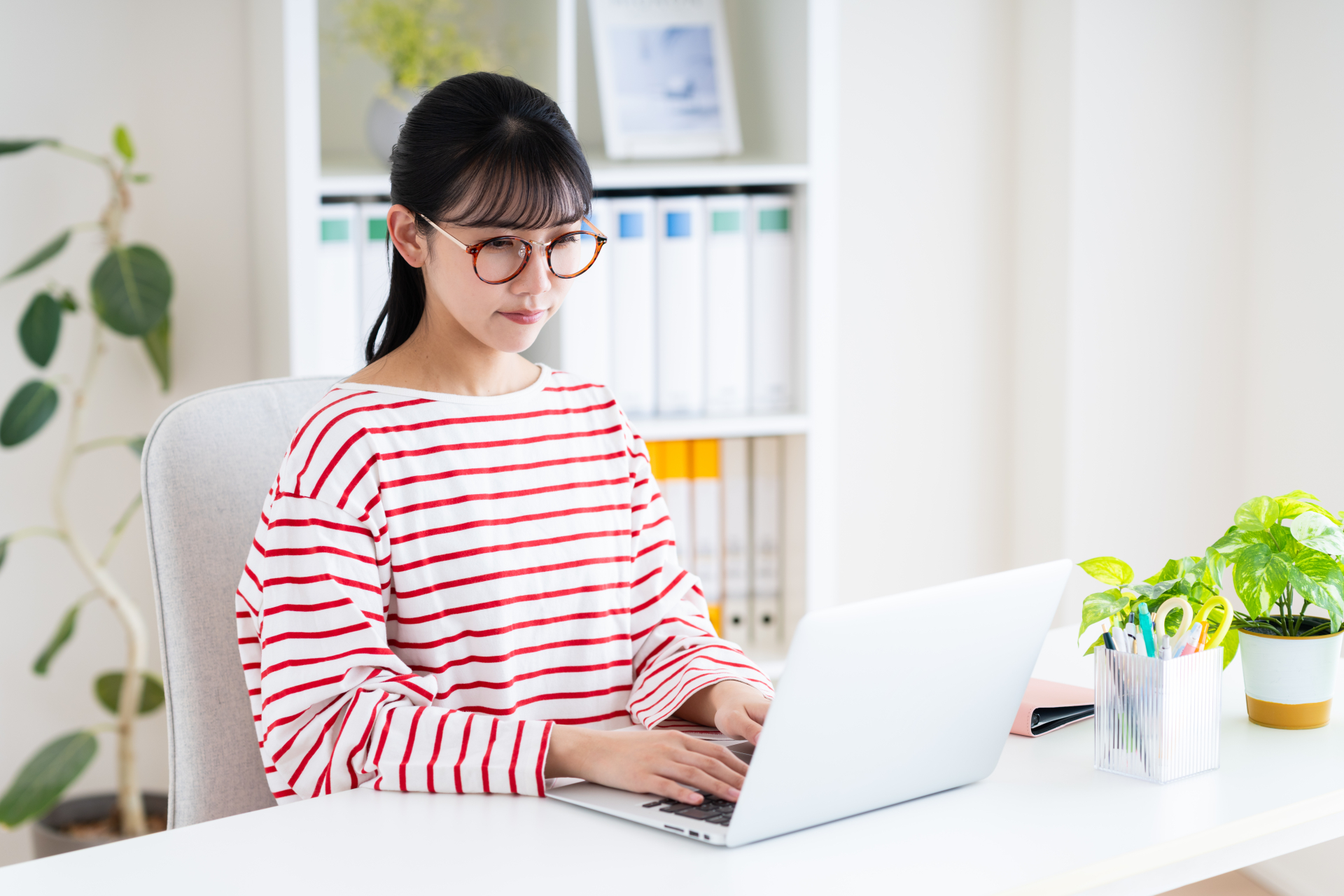 赤い眼鏡をかけてPCを操作している女性